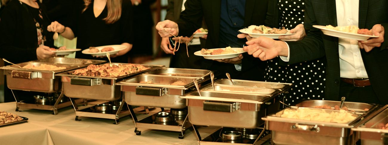Festlich gedecktes Buffet des Partyservice mit warmen Speisen und Gästen